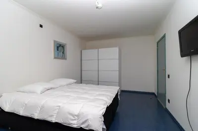 a bedroom with a white bed and a flat screen tv at Vakantiehuis Salamander Maasmechelen in Maasmechelen