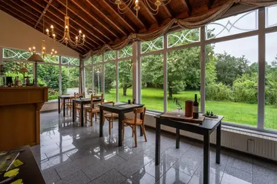 a dining room with tables and chairs and large windows at Logement de Blauwe Reiger in Voeren