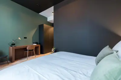 a bedroom with a large white bed and a desk at Vinotel X in Tongeren