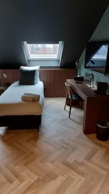 a bedroom with a bed and a desk and a window at Vinotel X in Tongeren