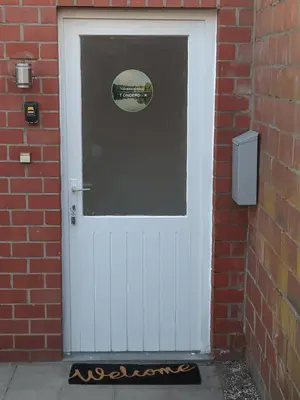 a white door in a brick building with a window at 'T ONDERDAK in Lommel