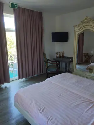 a bedroom with a bed and a mirror and a table at Kanne&kruike in Riemst