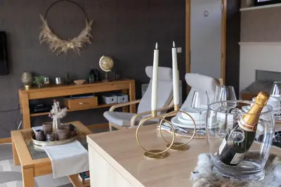 a living room with a table with a bottle of champagne at Le Petit Logis in Jalhay