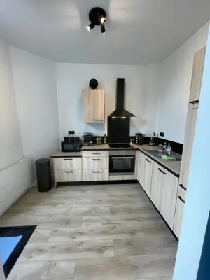 a kitchen with white walls and wooden cabinets at Patenier Hidden Garden 1bdr with garden in Liège
