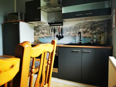 a kitchen with black cabinets and a sink and a table at Ferienwohnung in einem alten Bauernhaus in Lontzen