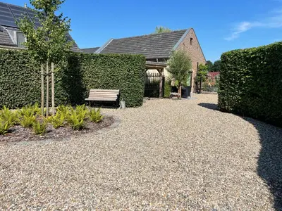 a garden with a bench in front of a hedge at Het Koerhuis in Kinrooi