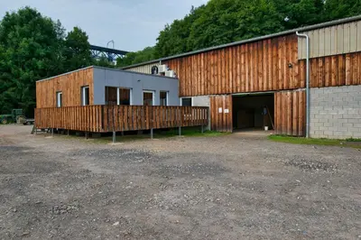 a building with a garage and a building with a fence at Le gîte de l'écurie des Saules in Plombières
