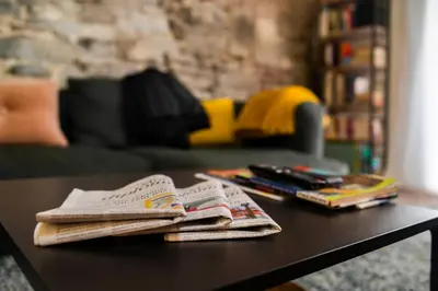 a coffee table with newspapers and books on it at L'atelier de Liège: Tranquillité & Effervescence in Liège