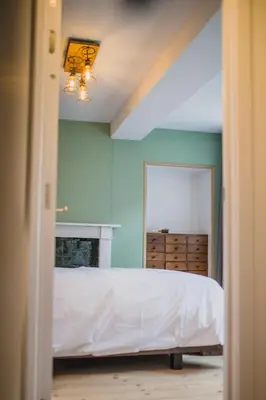 a bedroom with a white bed and a blue wall at Le Mayou in Mortroux