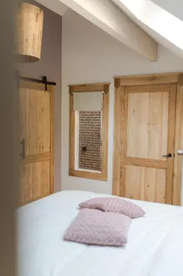 a bedroom with two doors and a bed with a pillow at Le Mayou in Mortroux