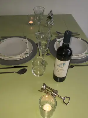 a green table with a bottle of wine and glasses at La Maison de Sidonie in Jalhay