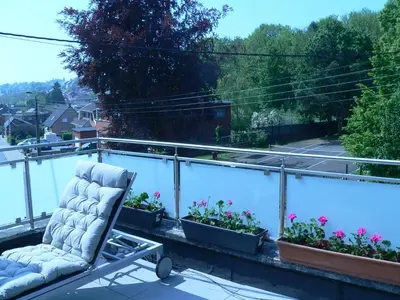 a chair sitting on top of a balcony with plants at liège 4420 rue jean Jaurès 45 grande maison joyeuse avec terrasse 30m2 pour 8 personnes maximum in Saint-Nicolas