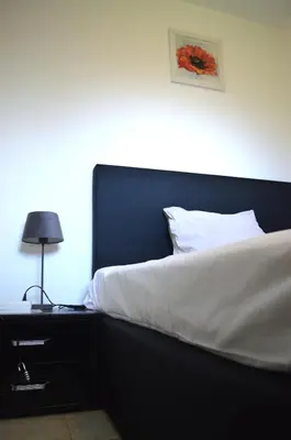a bed with white sheets and a lamp on a nightstand at Calme et verdure 9 in La Calamine