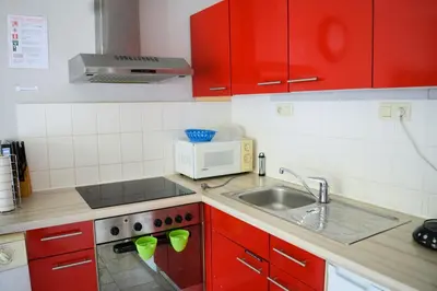 a kitchen with red cabinets and a sink and a microwave at Calme et verdure 9 in La Calamine