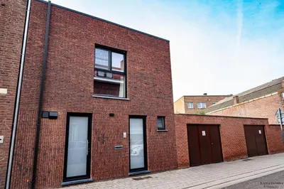 a red brick building with two windows and a balcony at Vakantiewoning Xalot in Tongeren