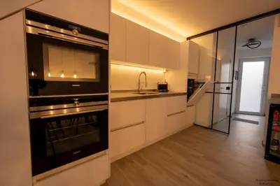 a kitchen with white cabinets and a sink and an oven at Vakantiewoning Xalot in Tongeren