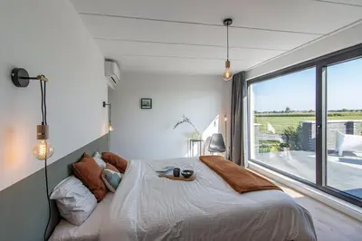 a bedroom with a large bed and a large window at Villa veld en velo in Bree