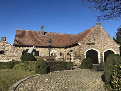 a large brick building with a cobblestone driveway at 14P 5B Villa de Poothoeve with Sauna and beautiful garden in Bilzen