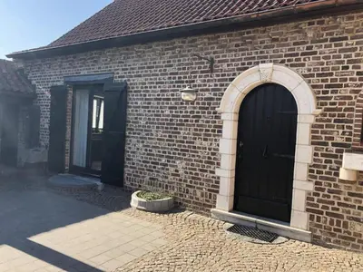 a brick building with a black door and windows at 14P 5B Villa de Poothoeve with Sauna and beautiful garden in Bilzen