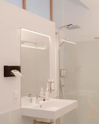 a white bathroom with a sink and a mirror at La Maison de Chestret in Liège