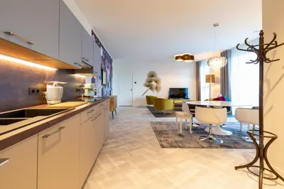 a kitchen with white cabinets and a dining room at GUILLEMINS STATION FLATS in Liège
