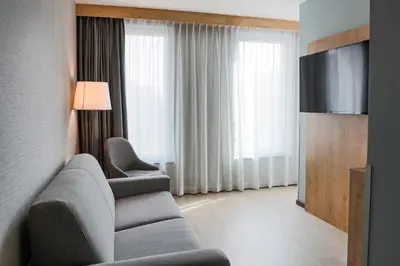 a living room with a couch and a flat screen tv at Radisson Hotel Liege City Centre in Liège