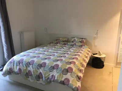 a bed with a colorful comforter in a bedroom at Le temps d’une balade. in Olne