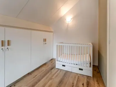 a white crib in a room with wooden floors at Heers Retreat with Sauna in Heers