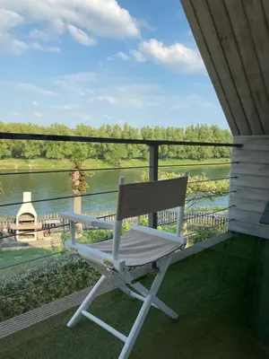 a white chair sitting on a porch overlooking a river at Ons Maashuisje in Maaseik