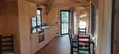 a kitchen with wooden cabinets and a table and chairs at Chalet Duras in Sint-Truiden