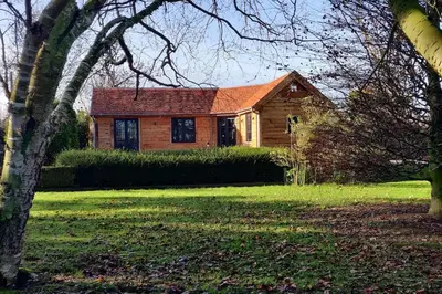 a wooden house in a yard with a tree at Chalet Duras in Sint-Truiden