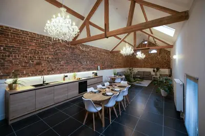 a kitchen with tables and chairs and a brick wall at Haspenhoeve Vakantiewoning in Herstappe