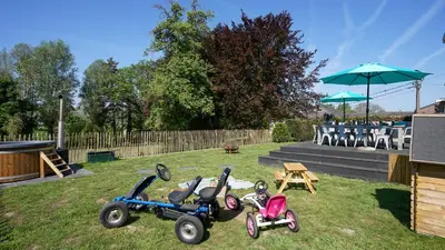 three childrens tricycles parked in the grass with an umbrella at SINTPIETER18 @Lo-Ghis vakantiewoning in Voeren