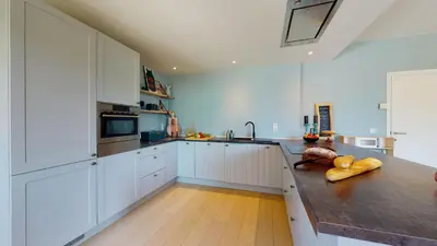 a large kitchen with white cabinets and a wooden floor at SINTPIETER18 @Lo-Ghis vakantiewoning in Voeren