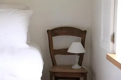 a wooden chair with a lamp next to a bed at Hoeve Luitenant Halleux in Linter