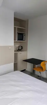 a bedroom with a bed and a table and a microwave at Louis in Maaseik