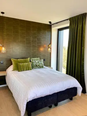 a bedroom with a large bed with green curtains at Le Clos du Verger in Aubel