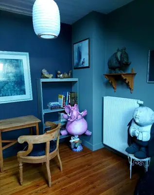 a room with blue walls and a chair and a book shelf at L'Atelier Bed and Breakfast in Andrimont
