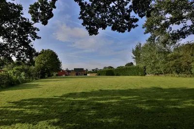 a large grassy field with trees in the foreground at Vakantiewoning Casa Maran in een groene omgeving te Heusden-Zolder in Heusden - Zolder