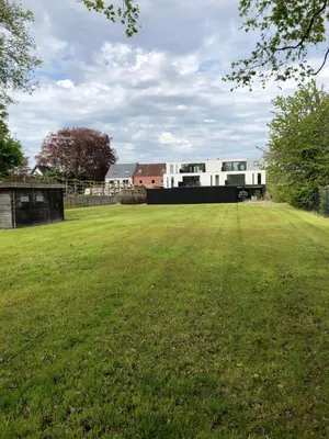 a large grass field with buildings in the background at Residentie Zeezicht in Eksel