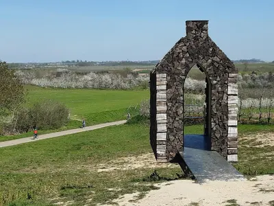 a stone archway in a field next to a road at Aan het Singelhof - Bellefleur*** met sunshower en tuin in Sint-Truiden
