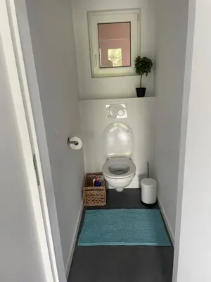 a small bathroom with a toilet with a blue rug at Guest House en famille ou en couple à la campagne in Romsée