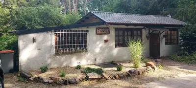 a small white building with a gate and a garden at 'T boshuisje in Oudsbergen