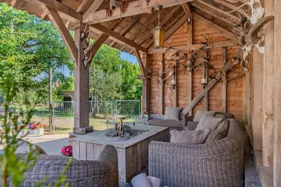 a wooden pergola with a table and chairs in a patio at Huize Koedoe in Tongeren
