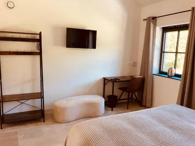 a bedroom with a bed and a desk with a television at De Molenhoeve B&B in Voeren