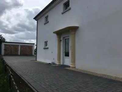 a white building with two columns and a door at Het Damhert in Kortenaken