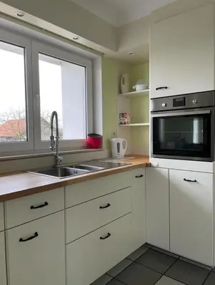 a kitchen with white cabinets and a sink and a microwave at Het Damhert in Kortenaken