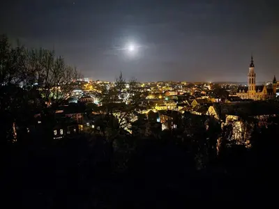 a view of a city at night with the moon at Suite Tino in Verviers