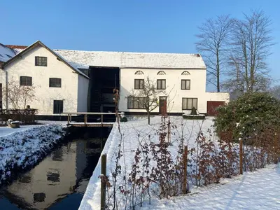 a house in the snow next to a canal at Vakantiewoning Wurfeldermolen in Maaseik