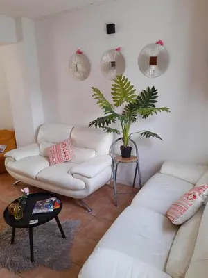 a living room with white couches and a potted plant at Agréable maison avec cour à 10min de Liège in Herstal